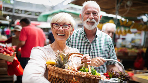 Ehepaar kauft auf dem Markt Obst & Gemüse ein
