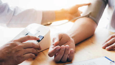 Arzt misst beim Patienten Blutdruck