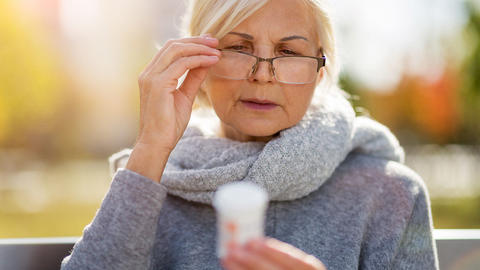 Frau schaut sich die Rückseite der Medikamentenverpackung an