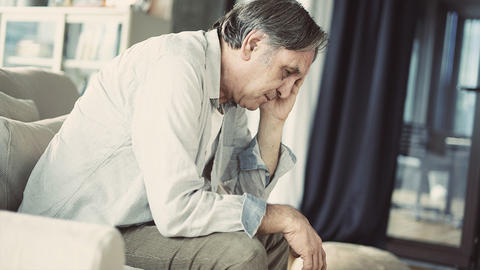 Mann sitzt erschöpft auf dem Sofa