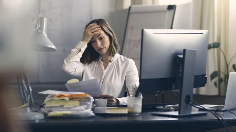 Frau verschränkt die Hand an dem Kopf vor viel Stress