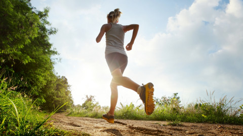 Frau joggt bei Sonnenschein im Wald