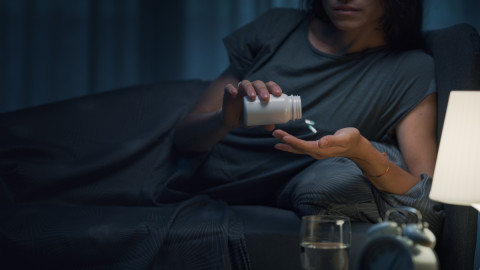 Frau nimmt zum einschlafen ein Medikament